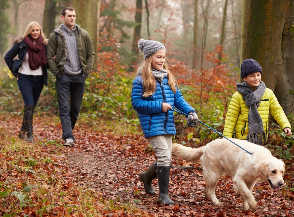 Fun for all the family these school holidays - a family dressed in warm clothes, taking their dog for a walk